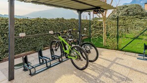 A covered bike parking area with two bicycles, a bike rack, and a view of a mountainous landscape. - Garda Oasis and Horizon by Interhome (Riva del Garda)