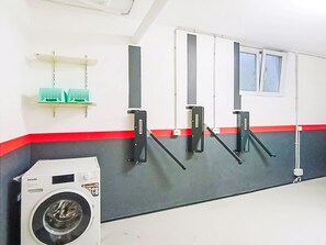 A laundry area with a washing machine, three wall-mounted drying racks, and a window with blinds. - Garda Oasis and Horizon by Interhome (Riva del Garda)