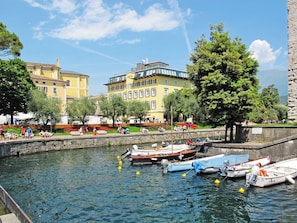 A waterfront with boats docked, a stone wall, and buildings with balconies. - Garda Oasis and Horizon by Interhome (Riva del Garda)