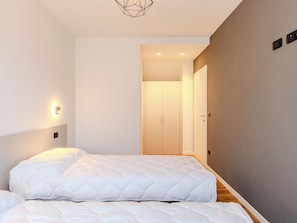 A bedroom with a bed, a wall-mounted light, and a door leading to another room. - Garda Horizon by Interhome (Riva del Garda)