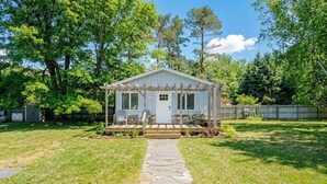 A small, single-story house with a porch, a stone pathway leading to the front door, and a fenced backyard.