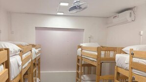 A room with bunk beds, a ceiling fan, an air conditioning unit, and a plain wall. - Hostel City Centre by Janatha (Colombo)