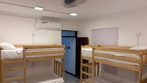 Two bunk beds in a room with a ceiling fan, an air conditioning unit, and a door. - Hostel City Centre by Janatha (Colombo)