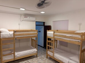 Huoneessa on kaksi kerrossänkyä, kattotuuletin, ilmastointilaite ja ovi.