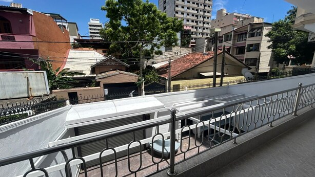 A pedestrian bridge with metal railings, a tiled roof, and buildings in the background. - Hostel City Centre by Janatha (Colombo)