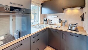 Une cuisine moderne équipée d’un four encastré, d’une machine à café et d’un évier.
