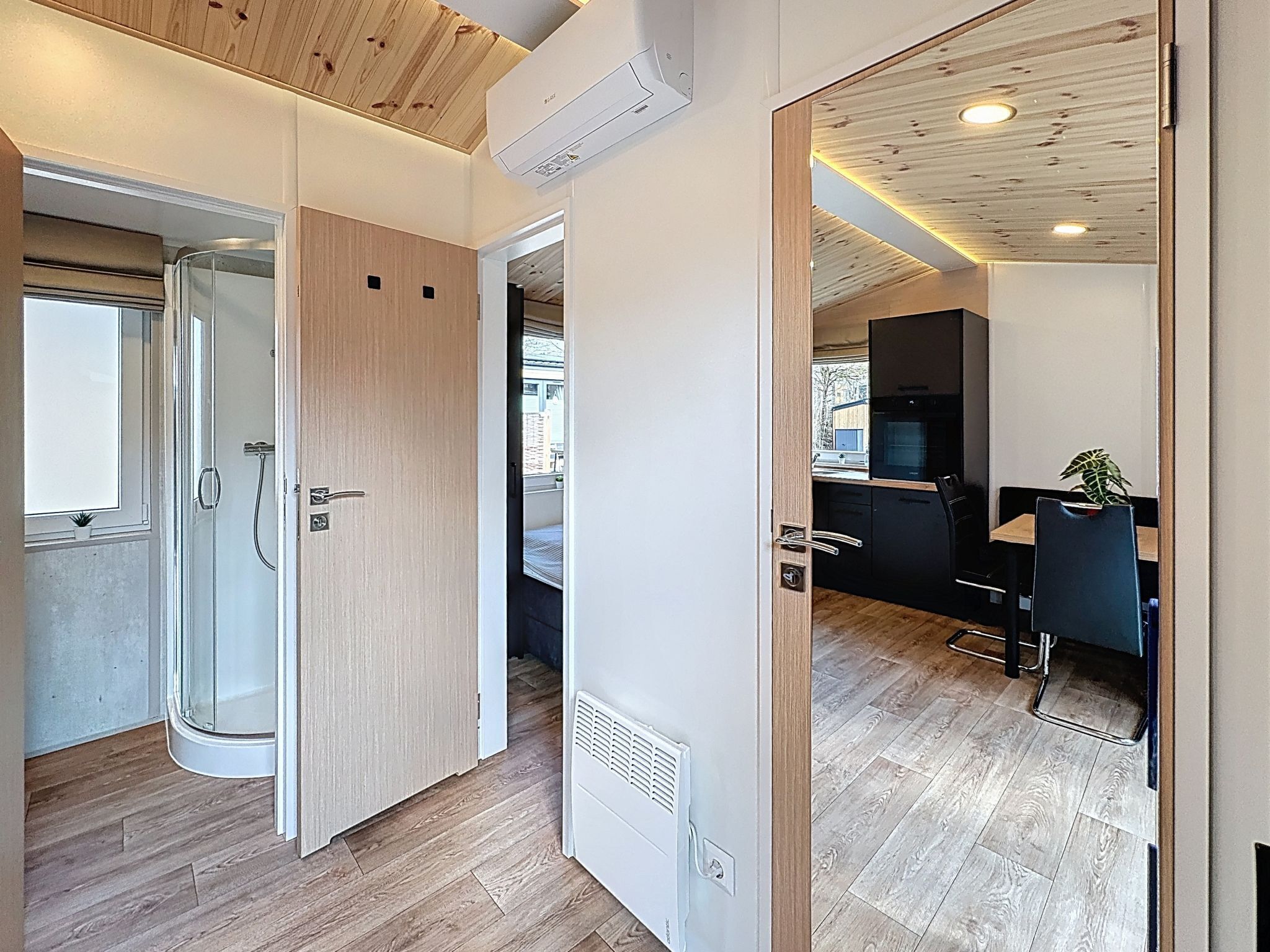 Ein modernes Interieur mit Holzbalkendecke, einer Duschkabine aus Glas und einer Küchenzeile.