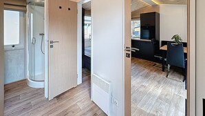 Un intérieur moderne avec un plafond en bois, une cabine de douche en verre et un coin cuisine.