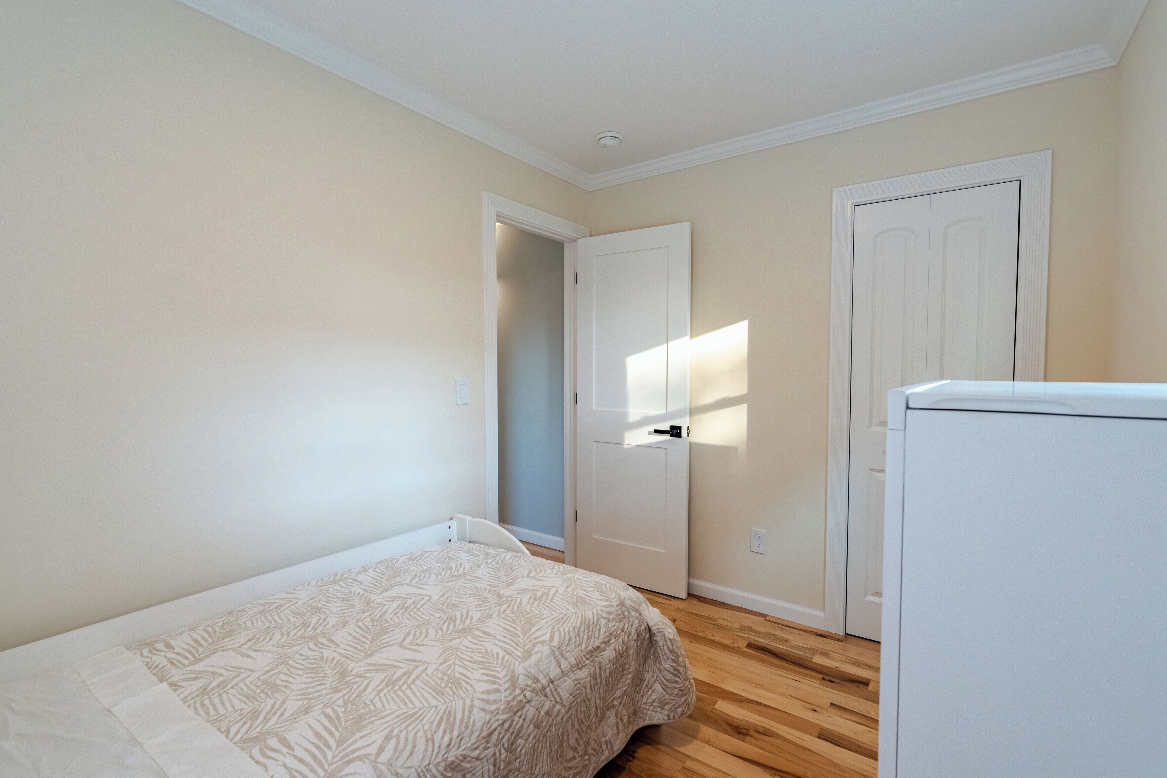 A bedroom with a bed, a door, and a white appliance.