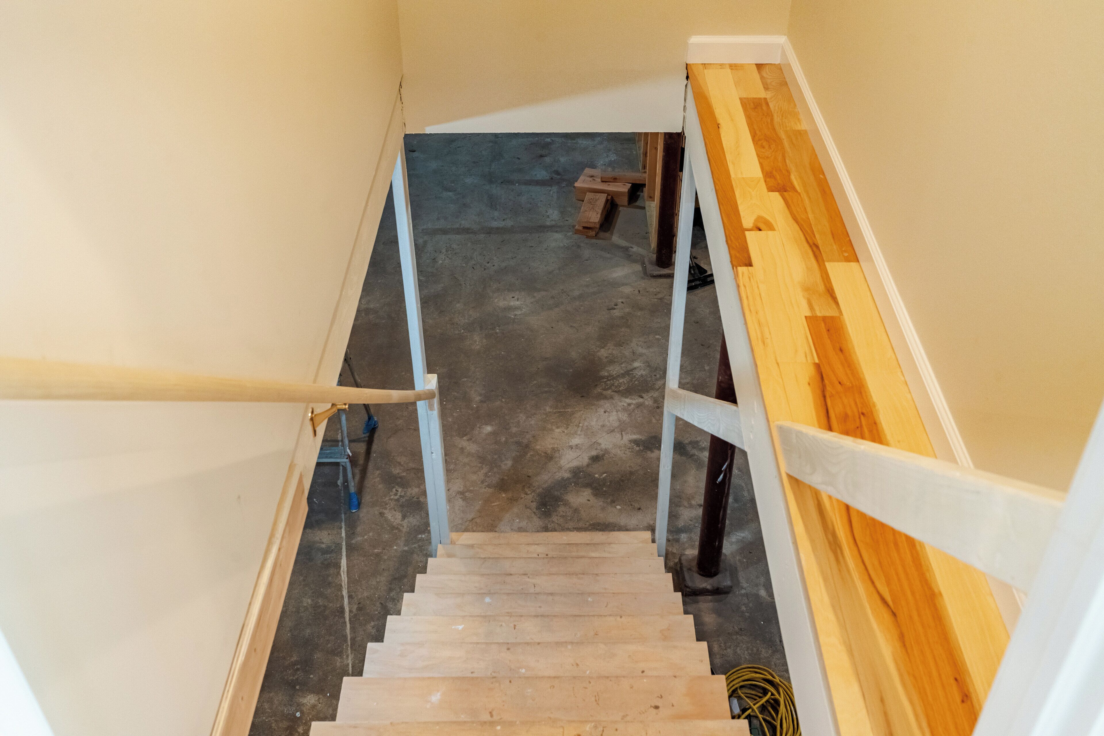 Un escalier en bois avec des rampes blanches, menant à un niveau inférieur.