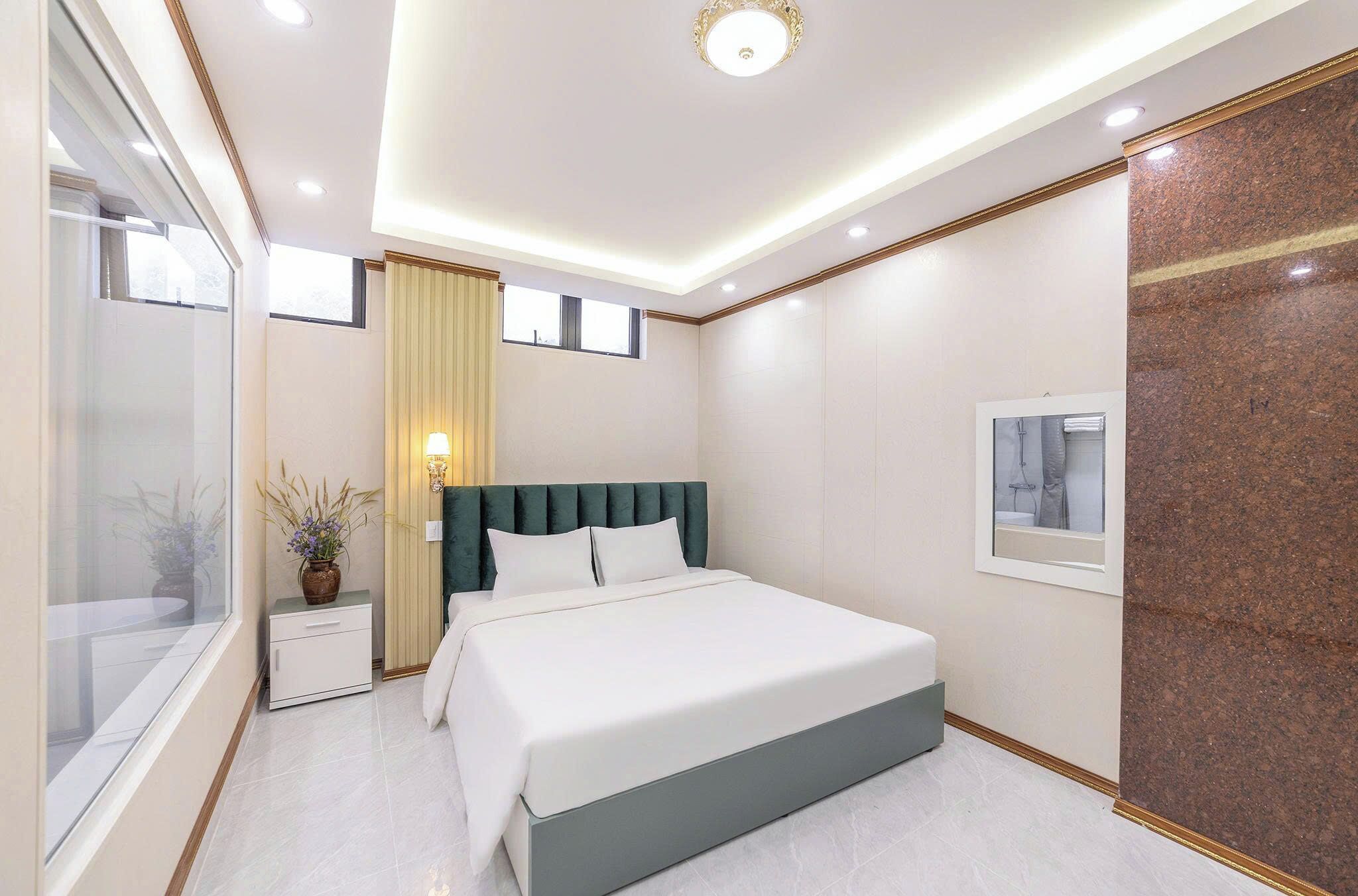 Una habitación de hotel moderna con cama, mesita de noche, lámpara y una ventana con cortinas.