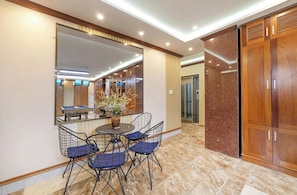 Un coin repas comprenant une table ronde, quatre chaises, un grand miroir et une armoire en bois.
