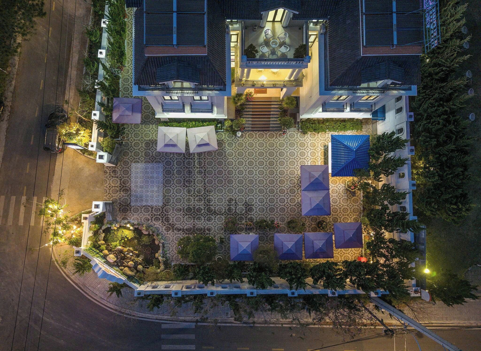 Vista aérea de un hotel con un patio central, mobiliario exterior y una estatua.
