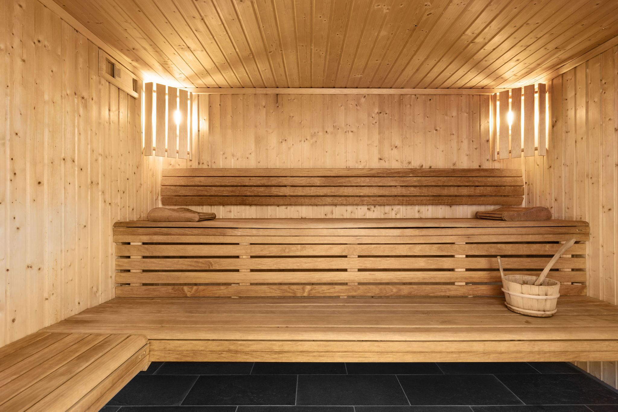 Una sauna in legno con panche e pavimento in pietra.