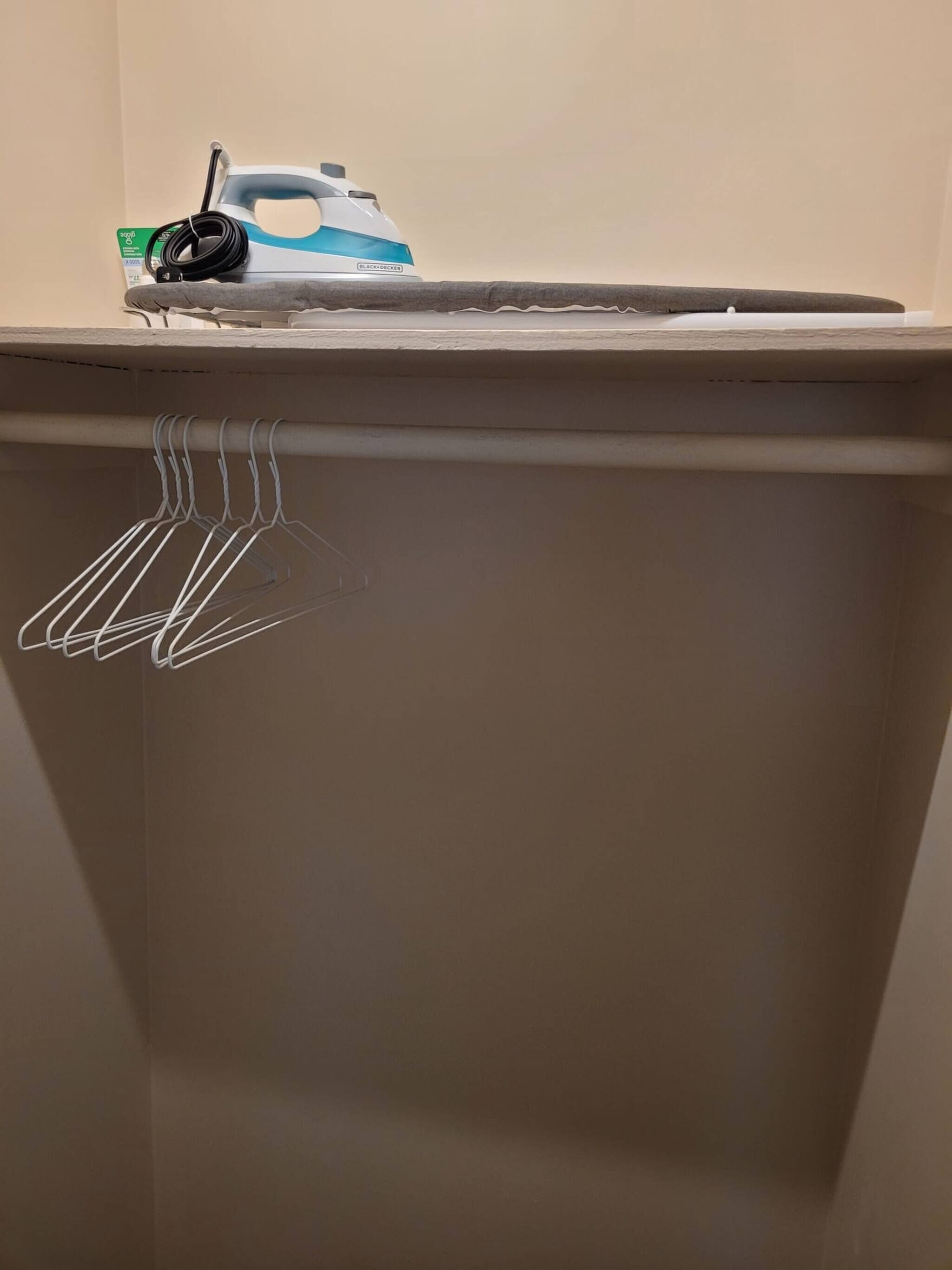 Eine Wand mit einer Whiteboard-Tafel, einer Steckdose und einem Metallregal.