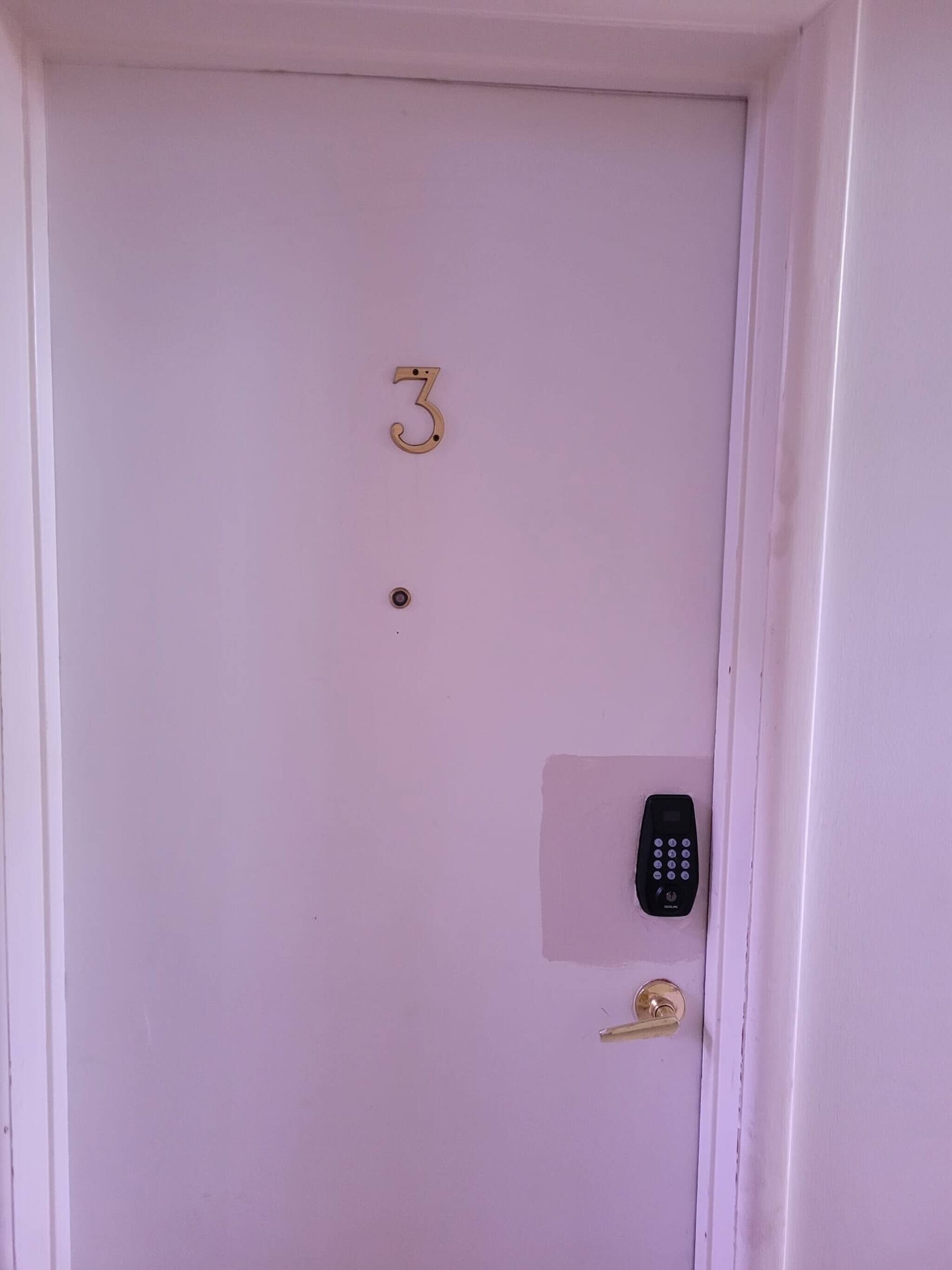 Uma porta branca com o número 3 e uma fechadura.