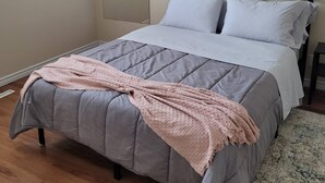 Ein Schlafzimmer mit einem Bett, einem Deckenventilator und einem Fenster.