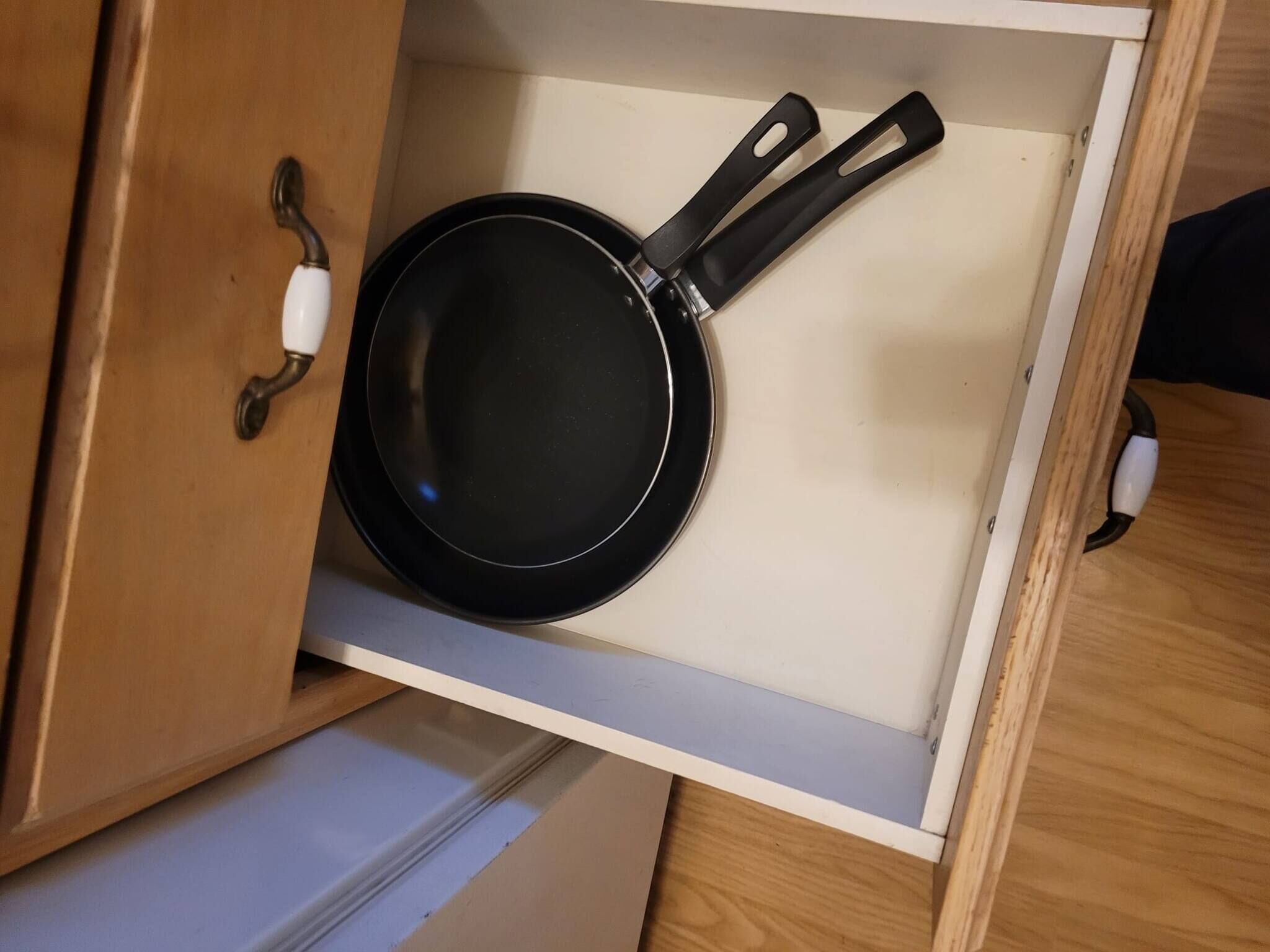 A drawer with a black frying pan inside.