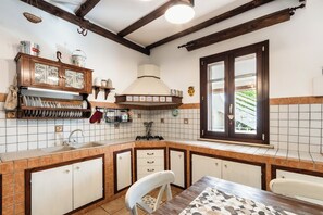 A kitchen with a wooden cabinet, a stove, and a window. - Two Steps from the Sea Down (Gallina)