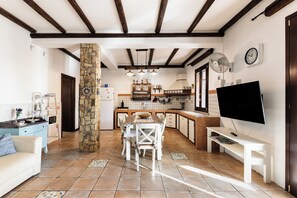 A spacious living area with a dining table, a sofa, a TV, and a kitchen in the background. - Two Steps from the Sea Down (Gallina)