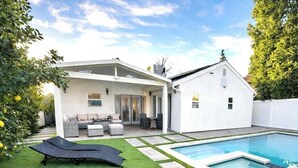 A modern house with a swimming pool, a patio with outdoor furniture, and a well-maintained lawn. - 3BR Retreat w/ Pool & Spa, Prime Tarzana Location (Los Angeles)