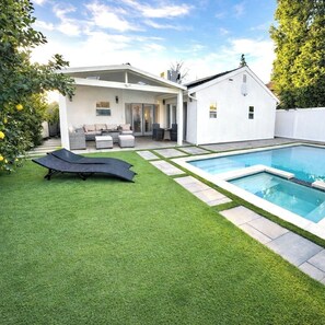 A modern house with a swimming pool, a patio with outdoor furniture, and a well-maintained lawn. - 3BR Retreat w/ Pool & Spa, Prime Tarzana Location (Los Angeles)