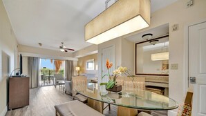 Une chambre d’hôtel dotée d’une table à manger en verre, d’un canapé, d’un ventilateur de plafond, d’une grande fenêtre et offrant une vue sur l’extérieur.