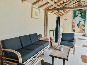 A room with a dark green sofa, two wicker chairs, a small wooden table with a potted plant, and a painting on the wall. - Spacious familyhouse with privat pool and slide (Lusignac)