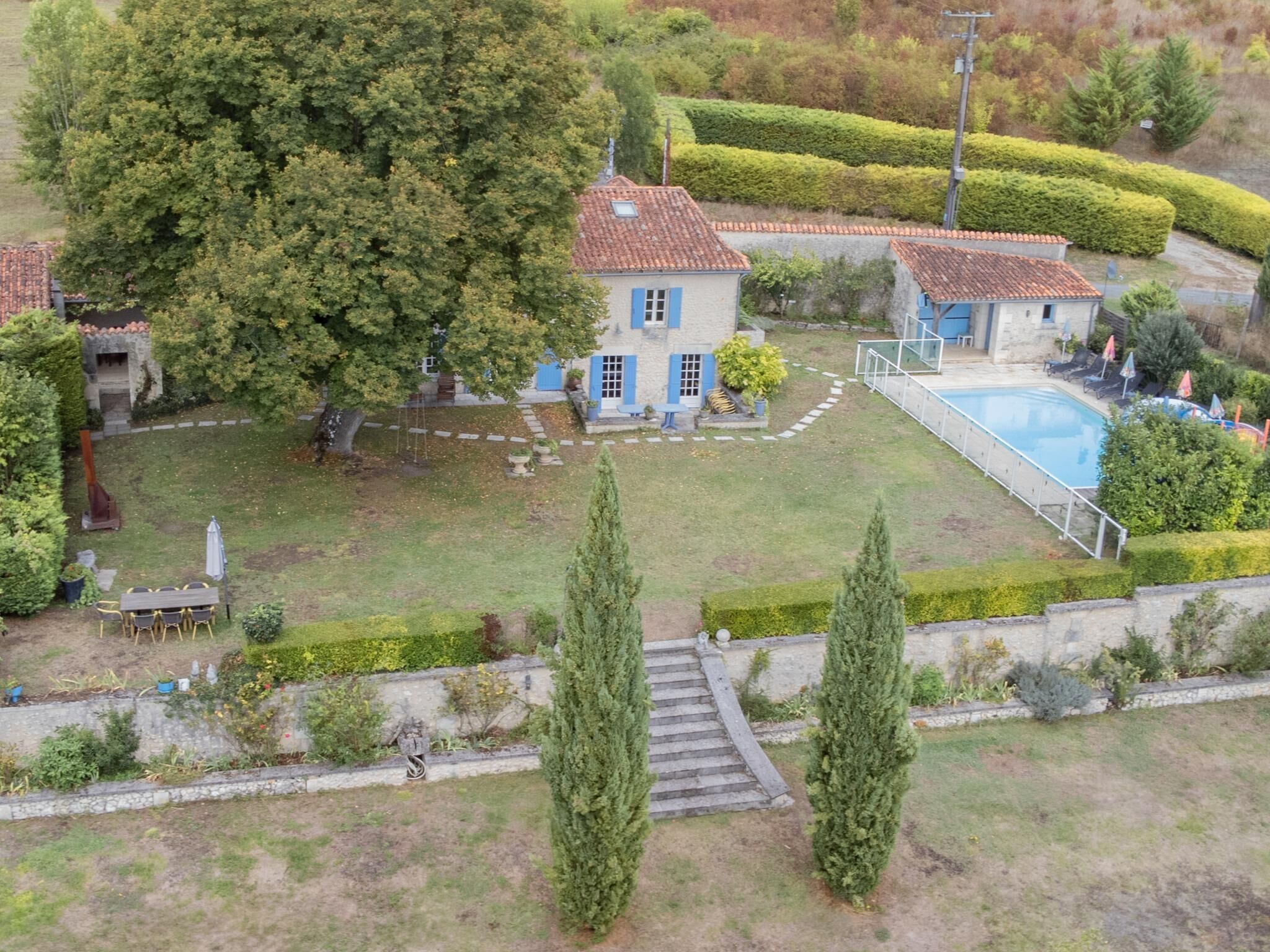 A residential property with a swimming pool, a garden with a lawn, and a stone pathway leading to the house.