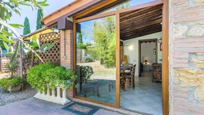 A modern building with a glass door entrance, a patio area with potted plants, and a visible dining area inside. - Preselle by Interhome (Casale Marittimo)
