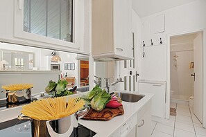 A modern kitchen with stainless steel appliances, a large window, and a view of the living area. - Casa Viola Garden in Losone for 4 (Losone)