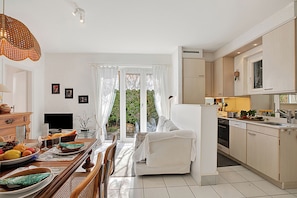 A modern kitchen with a dining area, a sofa, and a TV. - Casa Viola Garden in Losone for 4 (Losone)