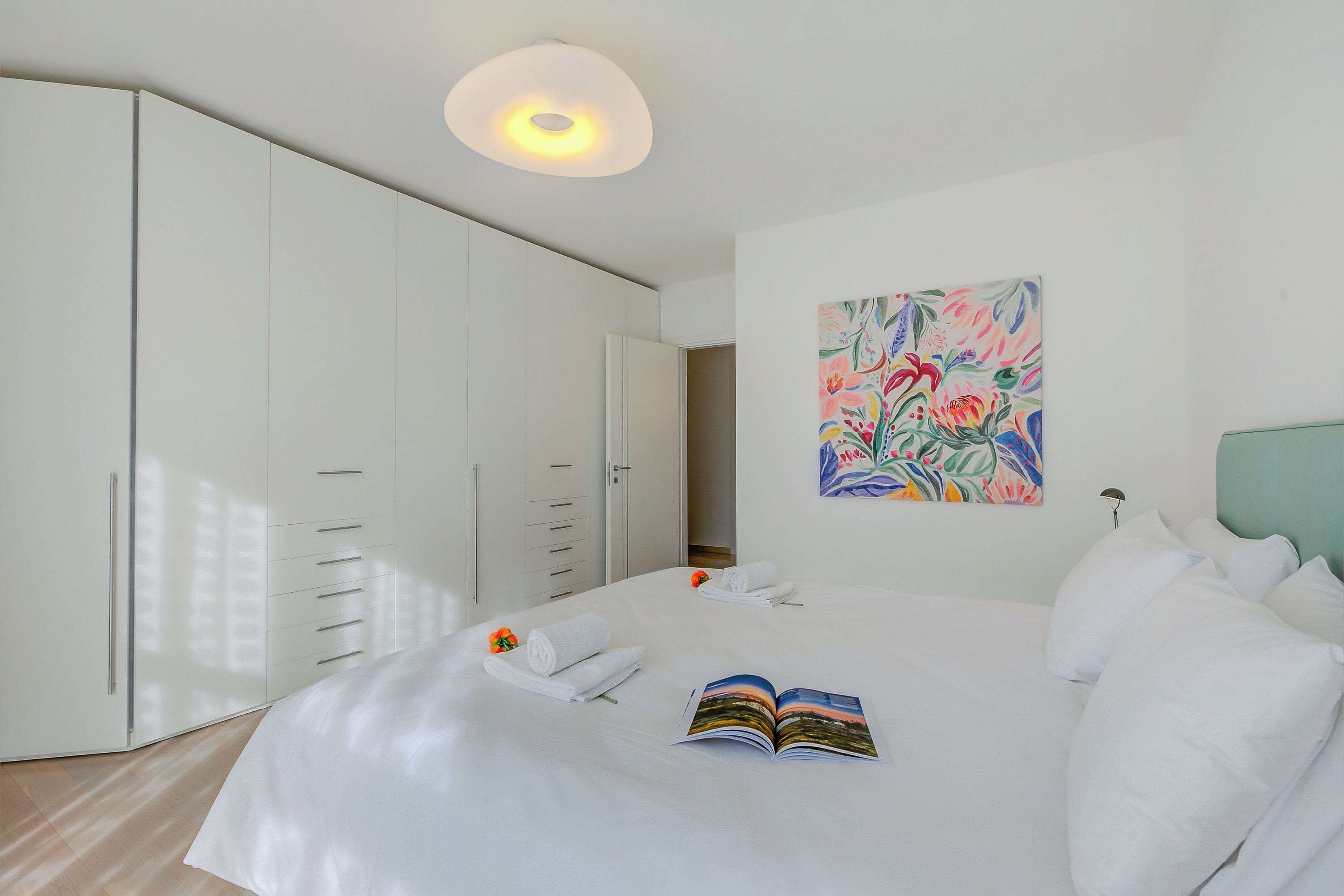 Habitació d'hotel amb un llit gran, un armari, un quadre a la paret i una làmpada al sostre.