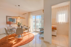 Una sala de estar moderna con comedor, ventanas amplias y un aparador de vidrio.