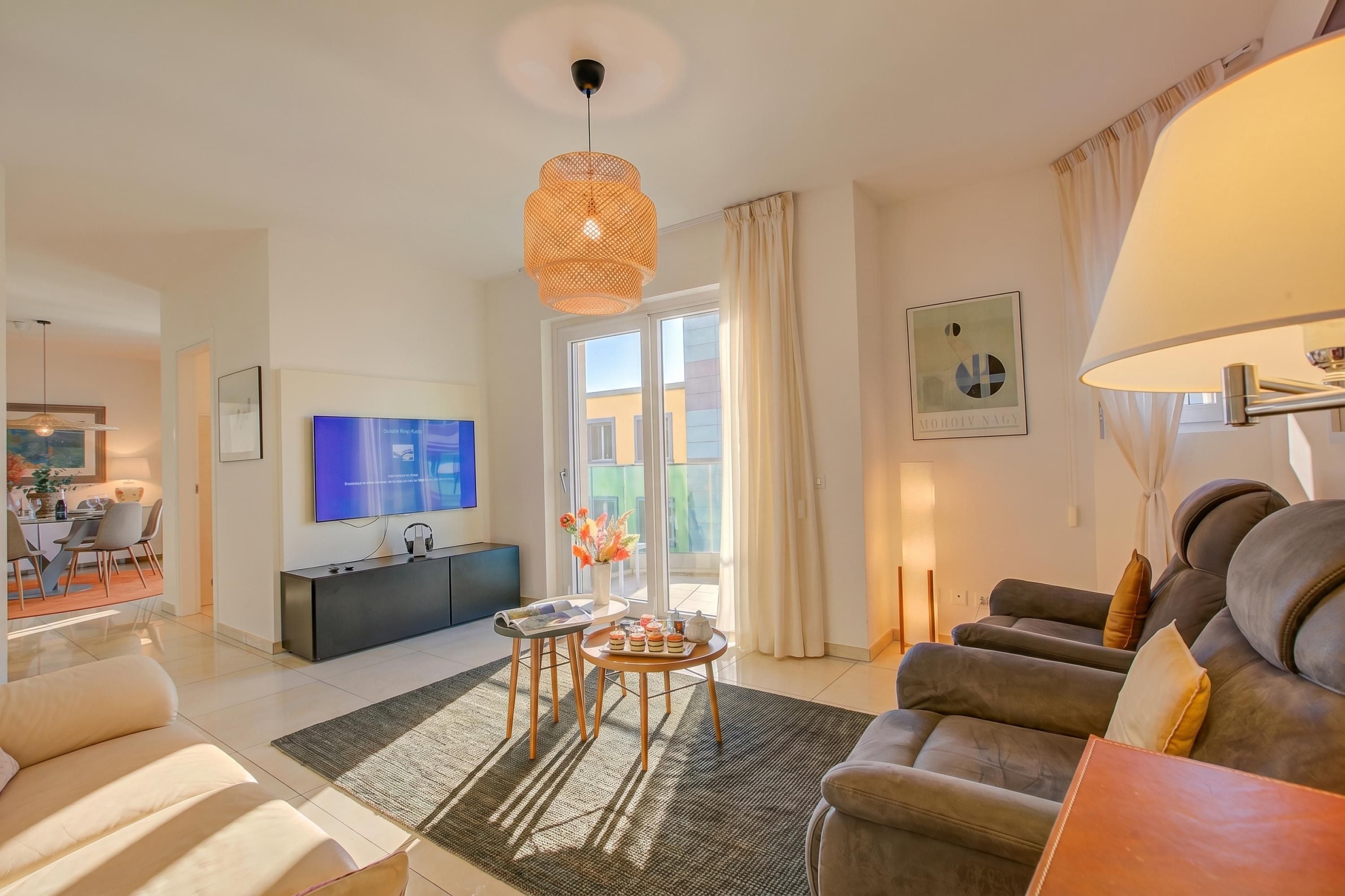 Ein modernes Wohnzimmer mit Sofa, Couchtisch, Fernseher und Essbereich.