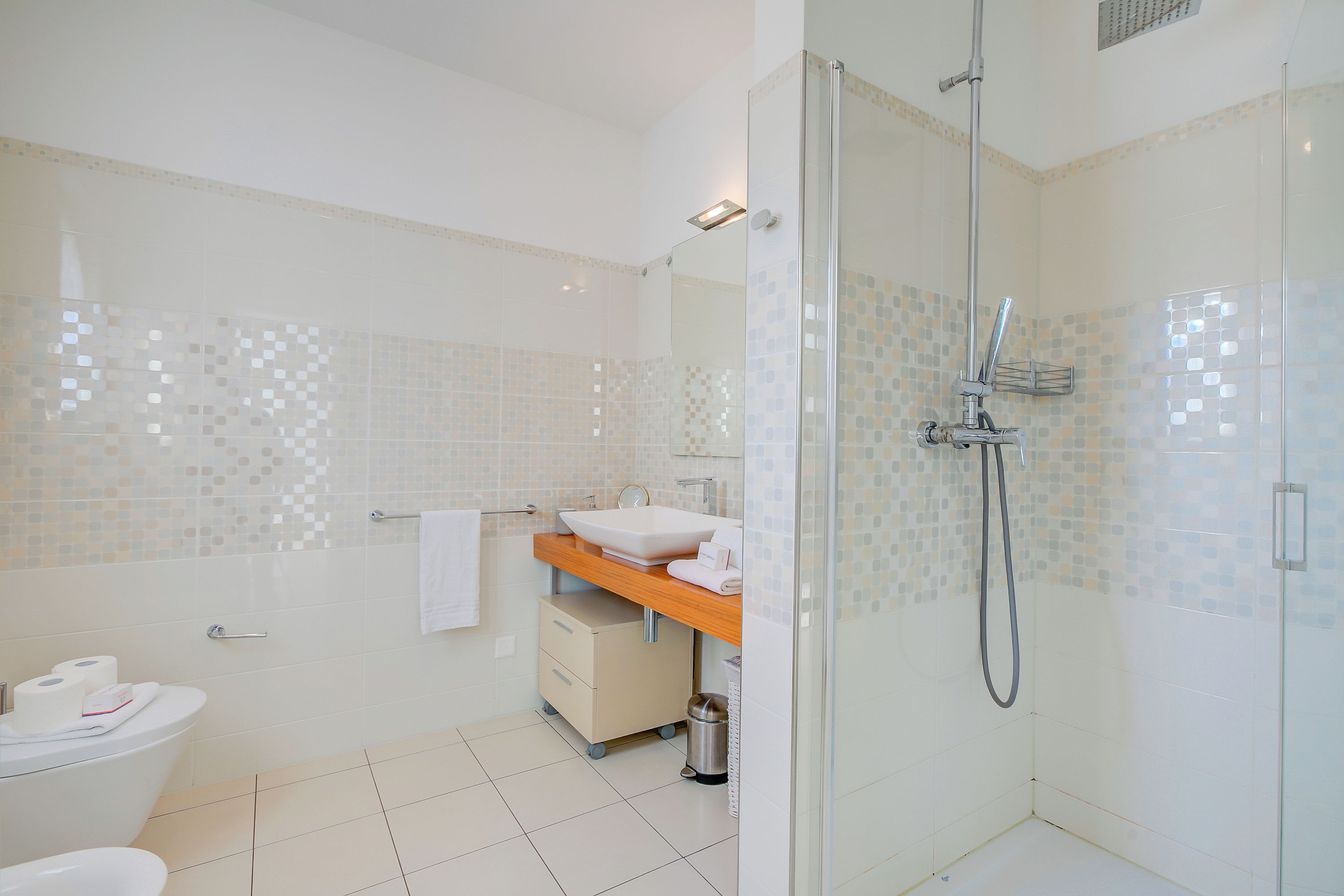 Ein modernes Badezimmer mit einer Duschkabine, einer Toilette und einem Waschbecken mit Spiegel.