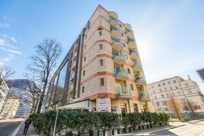 A multi-story hotel with balconies, a sign for 'Casa Emilia,' and a view of a hilly landscape. - Il Parco Exclusive - Apartment With Balcony & Views (Lugano)
