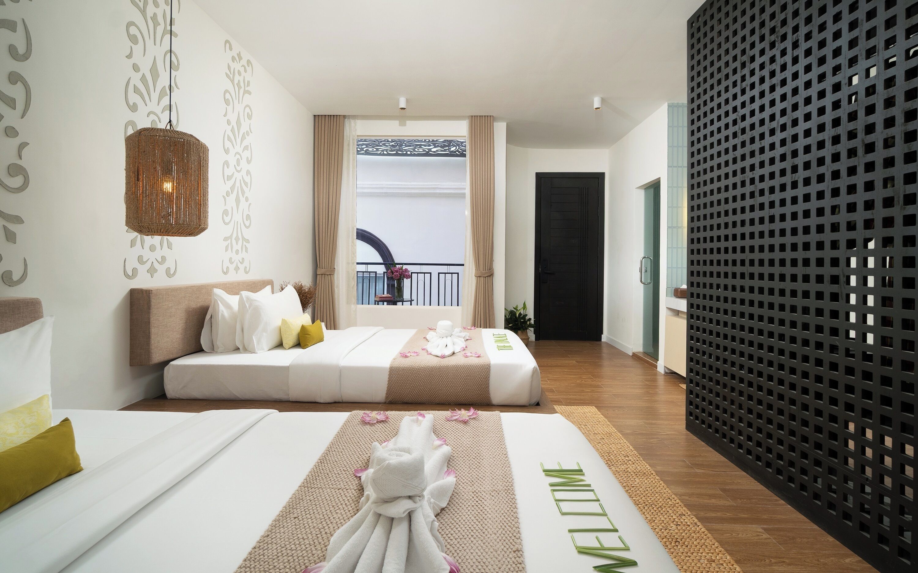 A hotel room with a bed, a decorative wall, a balcony with a railing, and a black partition.