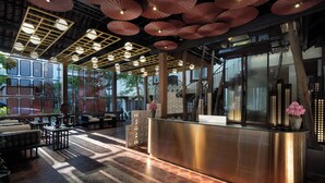 Un restaurante con una decoración moderna, que cuenta con una barra central, zonas de estar y vistas a la ciudad a través de amplios ventanales.