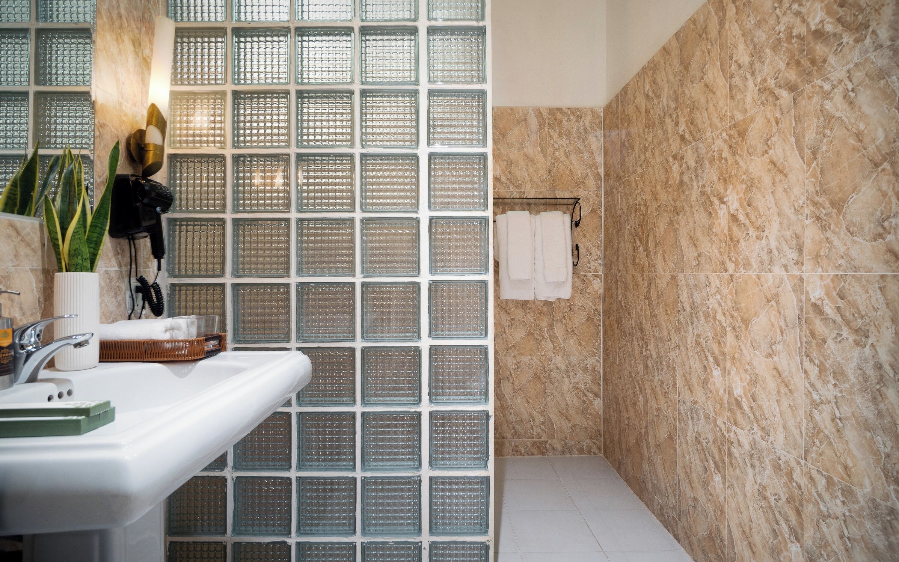 Un baño con pared de ducha azulejada, un lavabo con espejo y un perchero para toallas.