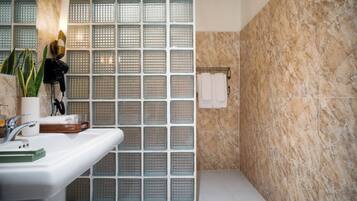Un baño con pared de ducha azulejada, un lavabo con espejo y un perchero para toallas.