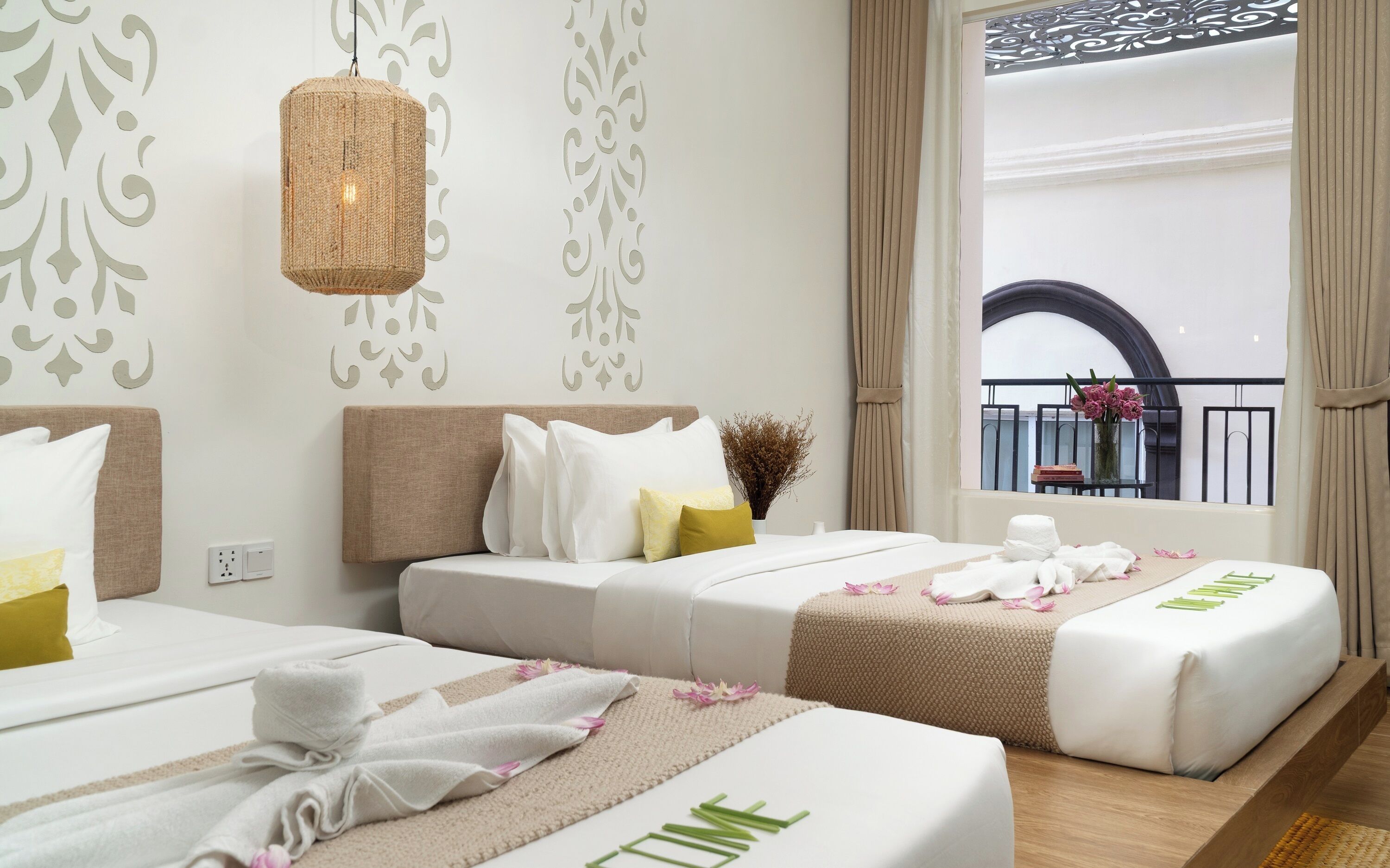 Habitación de hotel con dos camas, un balcón con vistas y diseños decorativos en la pared.