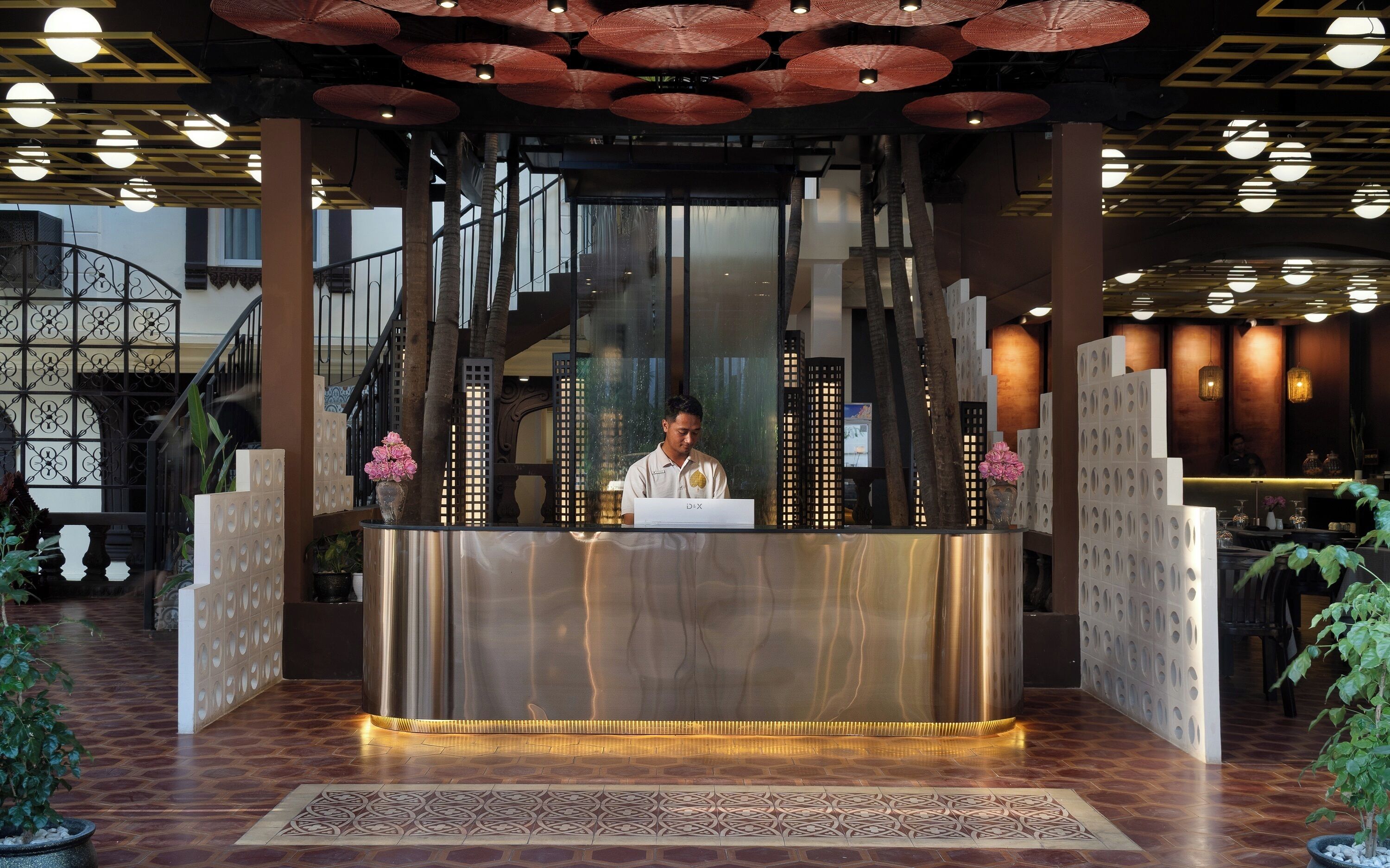 Un mostrador de recepción con diseño moderno, una escalera al fondo y una iluminación decorativa.