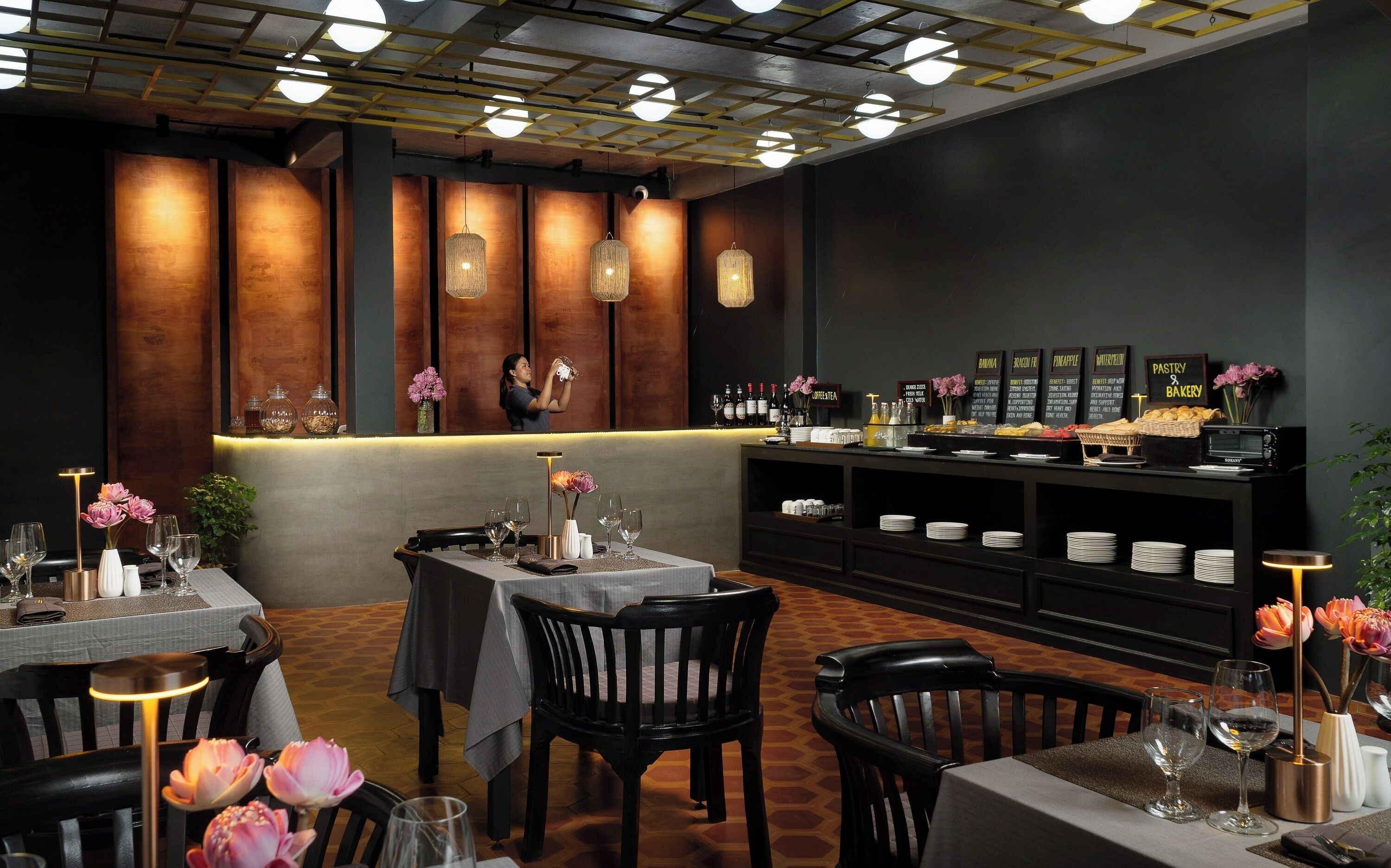 A restaurant interior with tables, chairs, a bar area, and a display of food and drinks.
