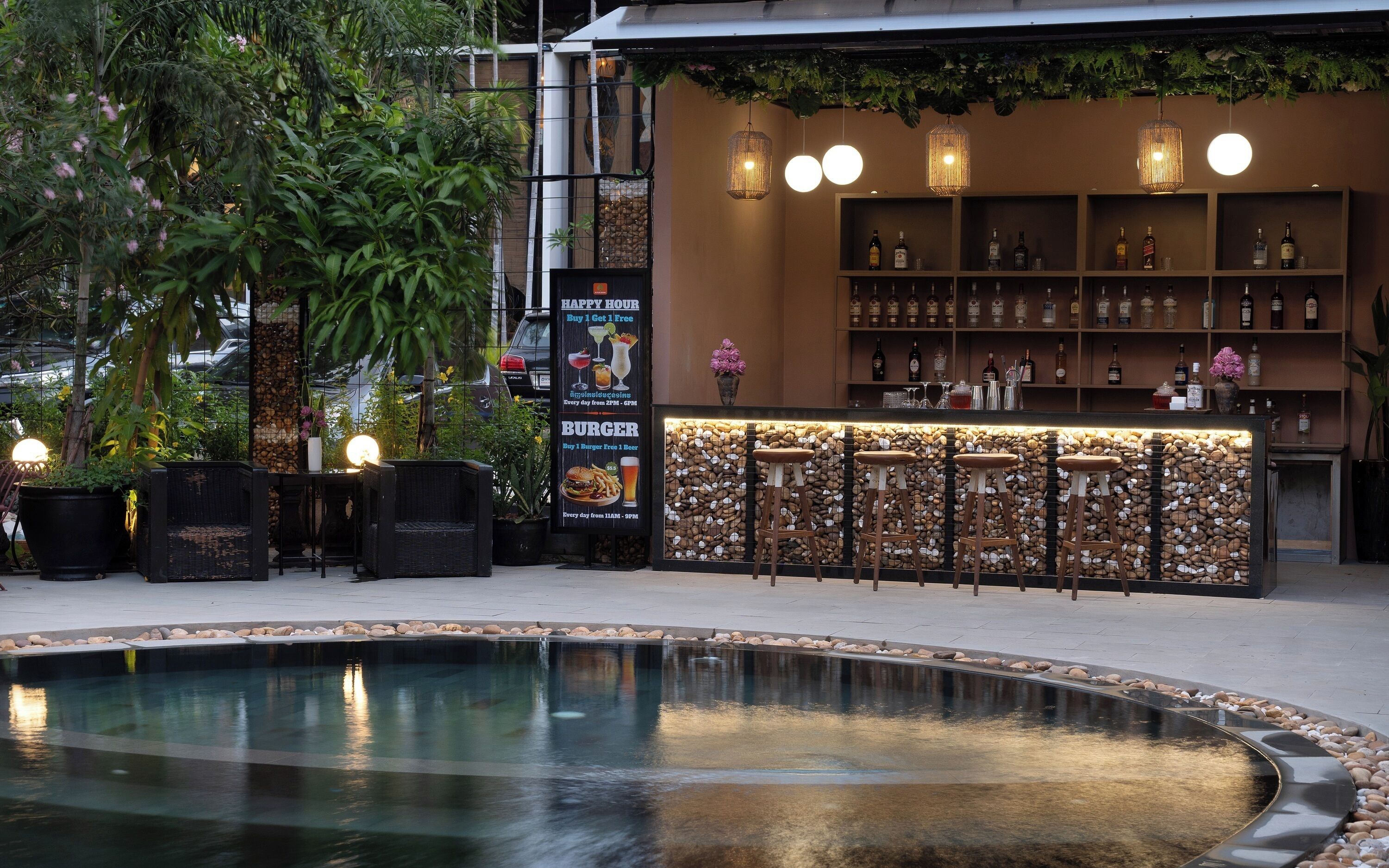 Eine Bar mit Pool, Barhocker und einer Auswahl an Flaschen in Regalen.