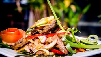 A plate of stir-fried meat with vegetables and a slice of lime.
