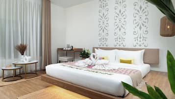 Una habitación de hotel con una cama grande, mesitas de noche y una pequeña mesa redonda con un florero y libros.