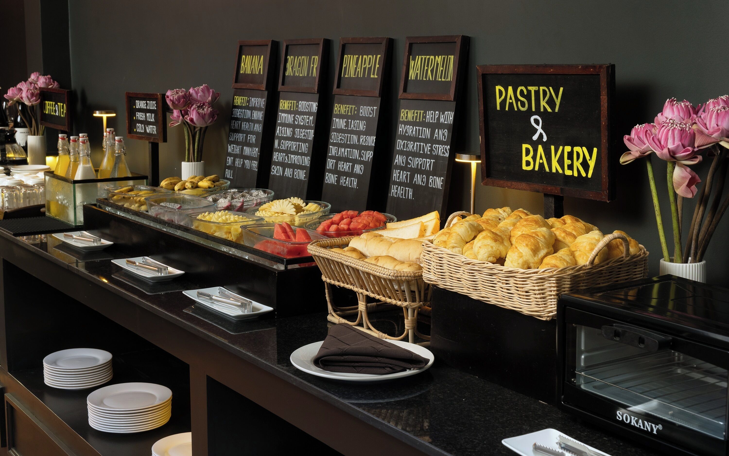A buffet with various fruits, pastries, and a sign indicating 'Pastry & Bakery'.