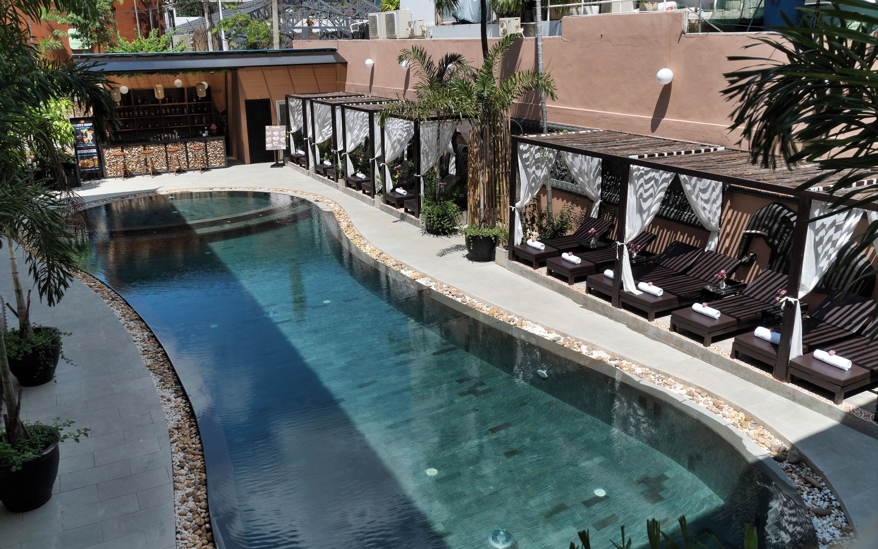 Une piscine avec des chaises longues et un espace bar.