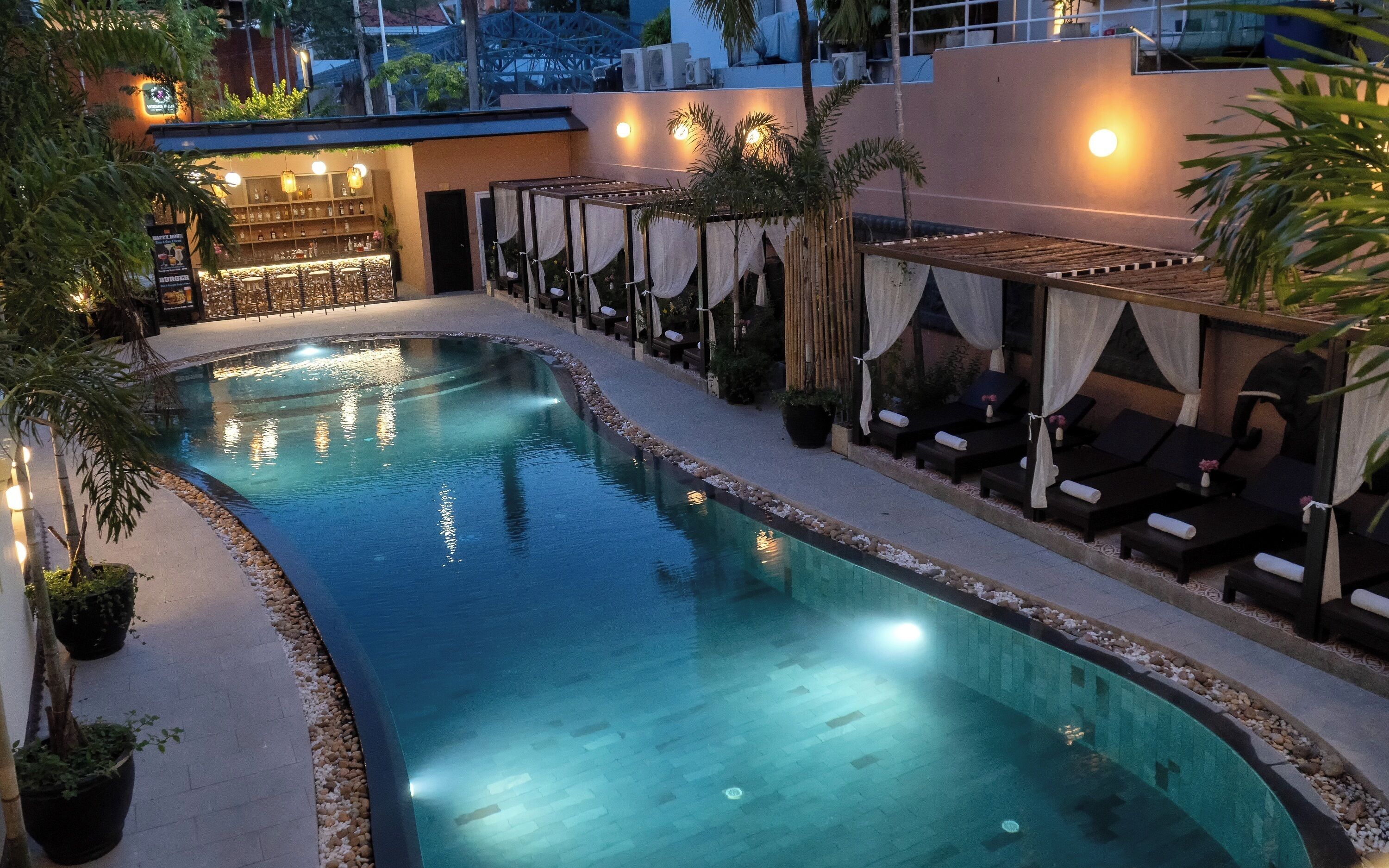 Une piscine avec des chaises longues et un espace bar.